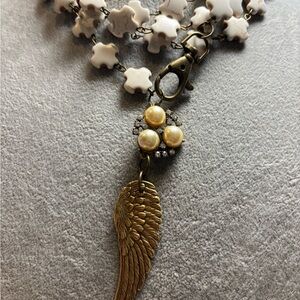 Elegant brass Wing Pendant Necklace with Cream cross throughout necklace!